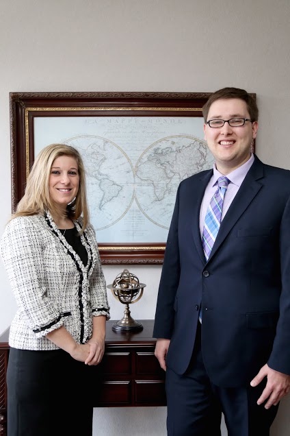 Attorneys Jennifer Fay and Brad Eberly standing before an antique world map